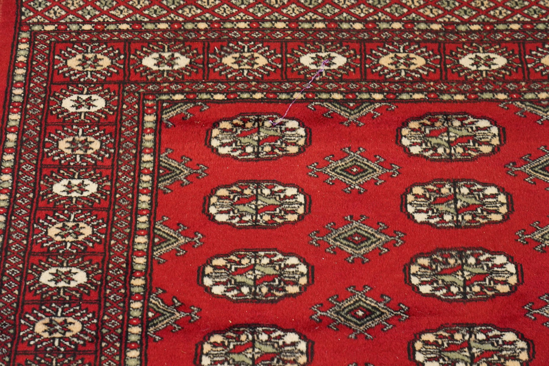 Two Afghan Bokhara crimson ground rugs, the fields decorated with repeating Gul motifs with geometric guard bands (126x190 & 157x250)