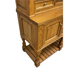 Light oak dresser, projecting cornice over display cabinets, shelves and drawers, the dresser base fitted with panelled cupboards and two drawers, on turned supports and pot board base