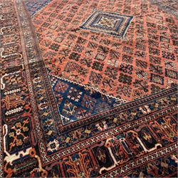 Joshgan Persian wool rug, with diamond-framed medallion, on a deep red field filled with geometric-shaped floral motifs and indigo-filled spandrels 