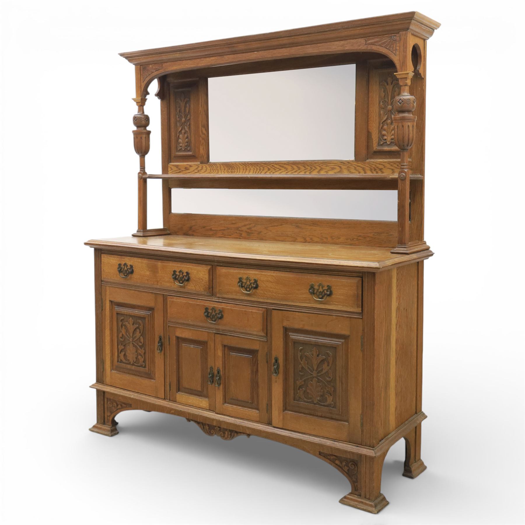 Arts and Crafts oak mirror back sideboard, the bevelled rectangular mirror set within a back with foliate carved panels, with turned baluster and knopped supports, upon a base with moulded top above three drawers  and three cupboard doors, two with carved foliate detail, upon four shaped bracket feet