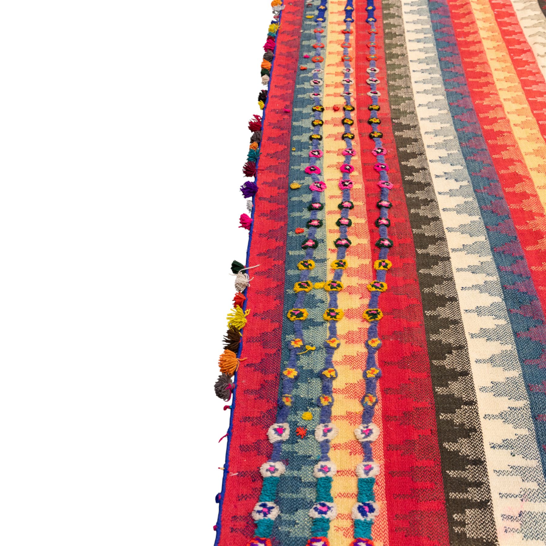South West Persian Jajim kilim flatweave runner, woven in warp-faced flatweave and composed of narrow bands, striped field in various shades of rose, coral, ivory, indigo, turquoise, and olive, embellished along the sides with applied knotted wool rosettes and tassels, some missing (due to large size, the runner is illustrated in two sections)