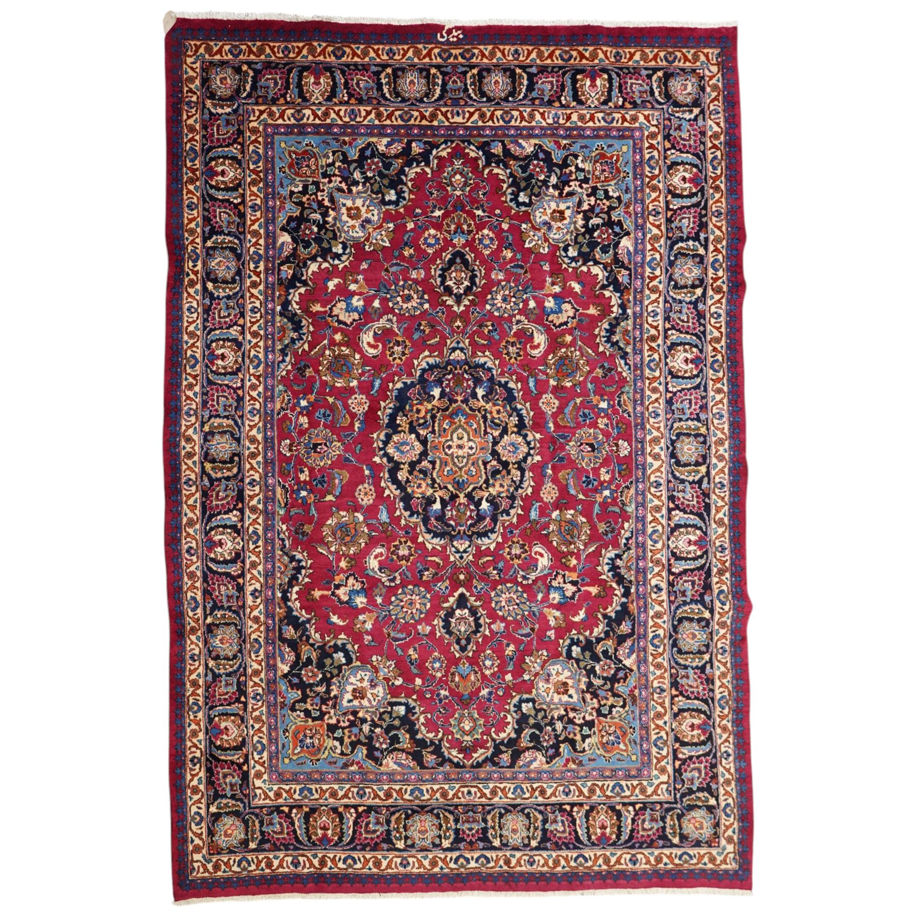 Central Persian Kashan hand-knotted carpet, rose red field, with central shaped lobed medallion issuing an all-over scrolling design of palmettes, floral sprays and arabesques, within conforming spandrels, enclosed by a broad indigo herati type palmette border framed by multiple guard stripes, in a palette of deep red, midnight blue and ivory tones, with cotton fringe ends, and Kashan signature 