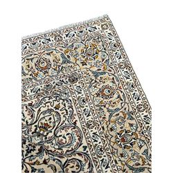 Persian Kashan ivory ground carpet, central pole medallion surrounded by swirling leafy branches and stylised plant motifs, scrolled foliate spandrels, the main border decorated with scrolling pattern and repeating palmettes, within floral patter guard stripes 