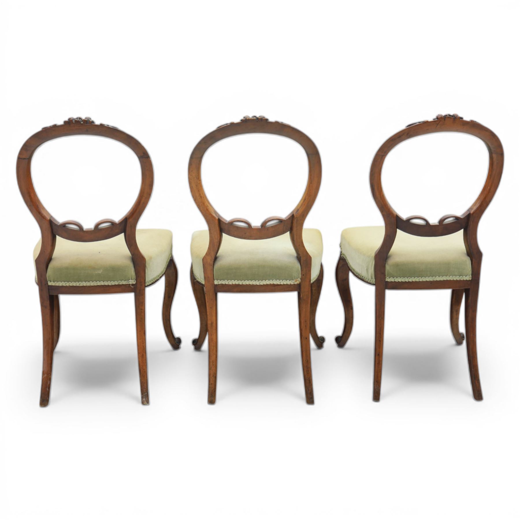 Victorian mahogany dining suite, oval tilt top dining table raised on a quatriform base with paw feet, together with a set of six balloon back dining chairs with green upholstery with cabriole legs 