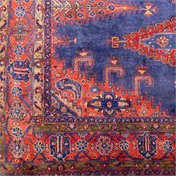 Central Persian Veis hand-knotted carpet, deep blue indigo field with central stepped lozenge medallion filled with stylized floral and geometric motifs, flanked by further angular medallions and tribal devices, edges with articulated and serrated hooked forms within a wide geometric border with repeating stylized floral motifs and multiple guard borders, in madder red, indigo blue, ivory, olive green, with cotton fringe ends