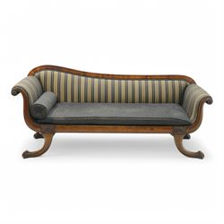 Regency brass inlaid rosewood chaise lounge or settee, shaped back over rolled head and foot, upholstered in black and gold striped fabric with rectangular squab cushion and bolster cushion, the rolled terminals carved with acanthus leaf roundels, lower rectangular foliate carved panels, on out splayed supports with paw carved feet 