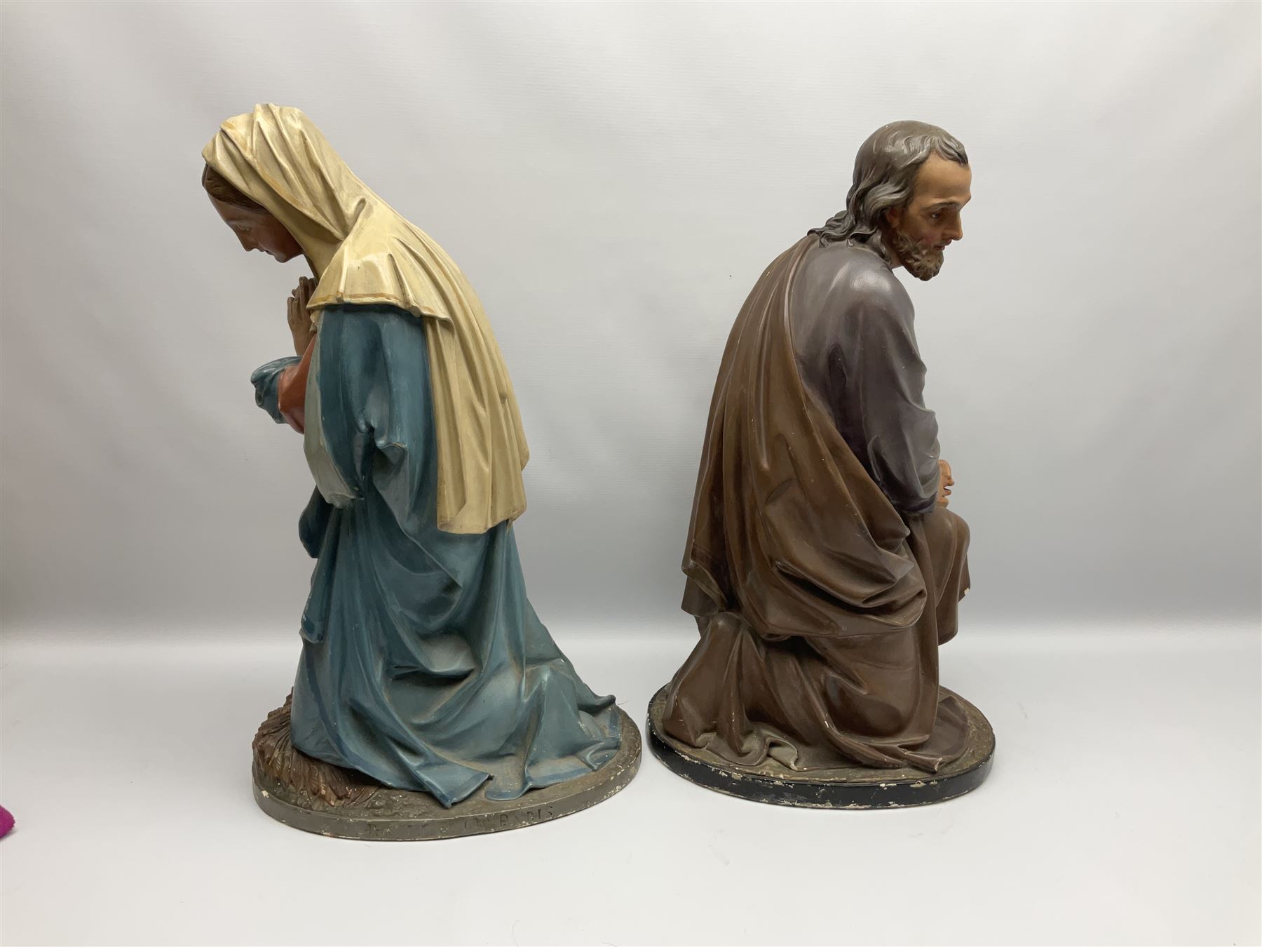 Two religious painted plaster figures of Mary and Joseph kneeling on oval plinths, with impressed mark 'Raffl et Cie Paris', H60cm 
