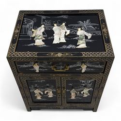 20th century Japanese Shibayama style black lacquered cabinet, rectangular form decorated with mother-of-pearl and hardstone figural inlay, the top with four standing figures, single frieze drawer above two cupboard doors, gilt painted borders and landscape