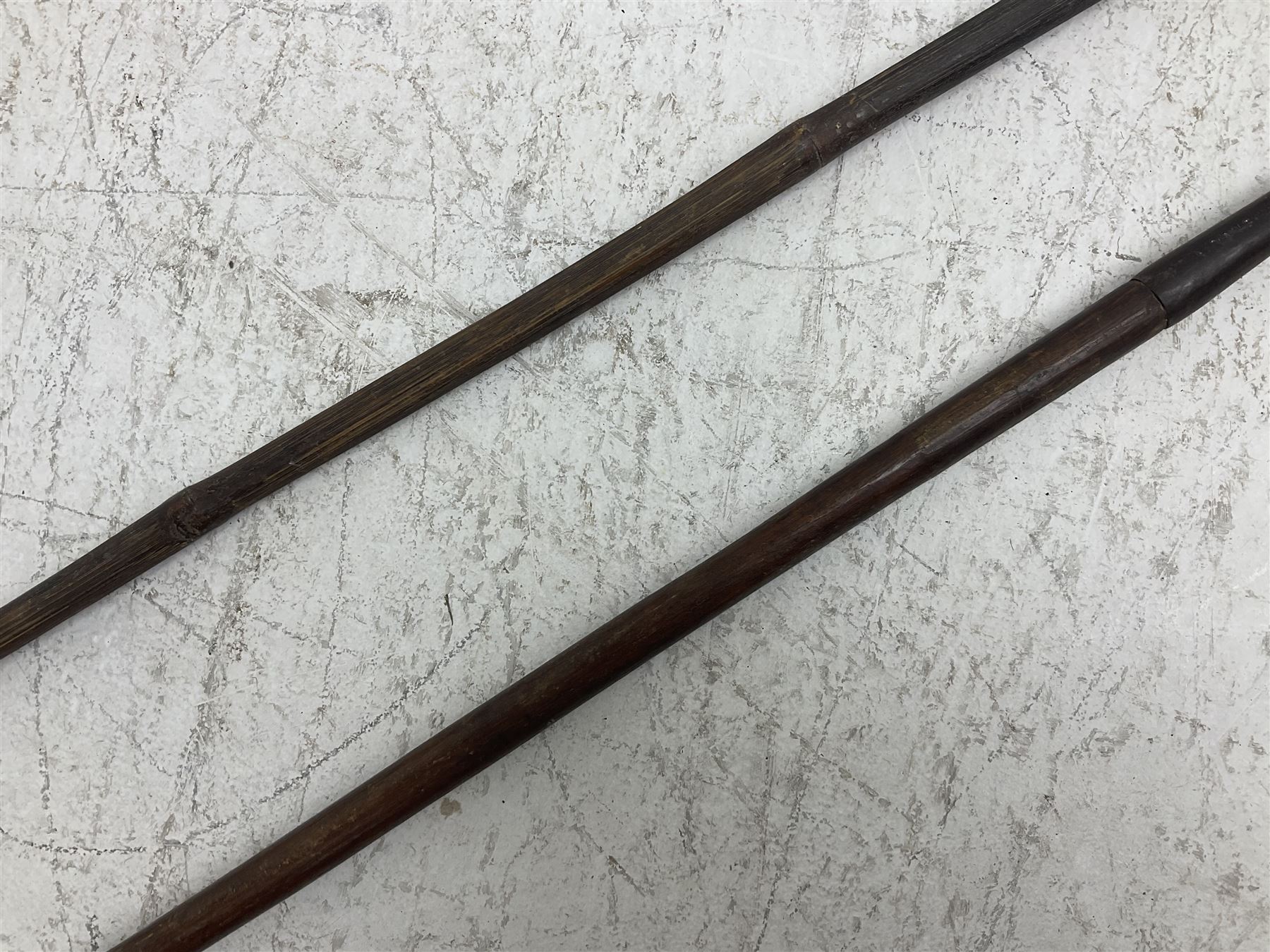 Native long-shafted spear, the large iron head with central medial ridge and decorative neck, on plain circular haft L260cm; and another similar Native long-shafted spear with cane haft L249cm (2)
