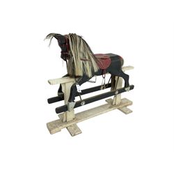 20th century black painted rocking horse on white painted trestle base, fitted with saddle and stirrups 