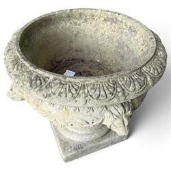 Regency design weathered cast stone garden urn of kylix form, the anthemion and arrowhead moulded everted rim over a fruiting laurel and lion-mask relief decorated body, waisted socle on square base, stamped HGC