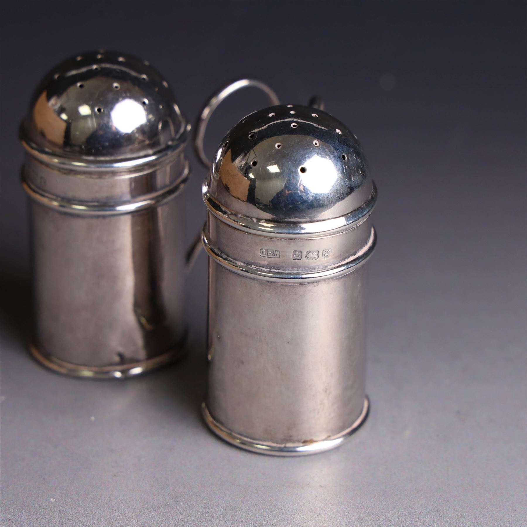 Pair of Edwardian silver muffineers, of cylindrical form with C scroll handles and removable pierced covers, hallmarked G E Walton & Co Ltd, Birmingham 1906, H6cm
