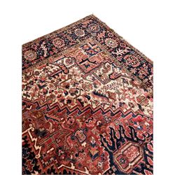 Persian Heriz red ground carpet, large stylised pole medallion surrounded by Pitrak motifs, indigo ground border decorated with stylised flower heads and trailing leafy branches, within floral pattern guard stripes