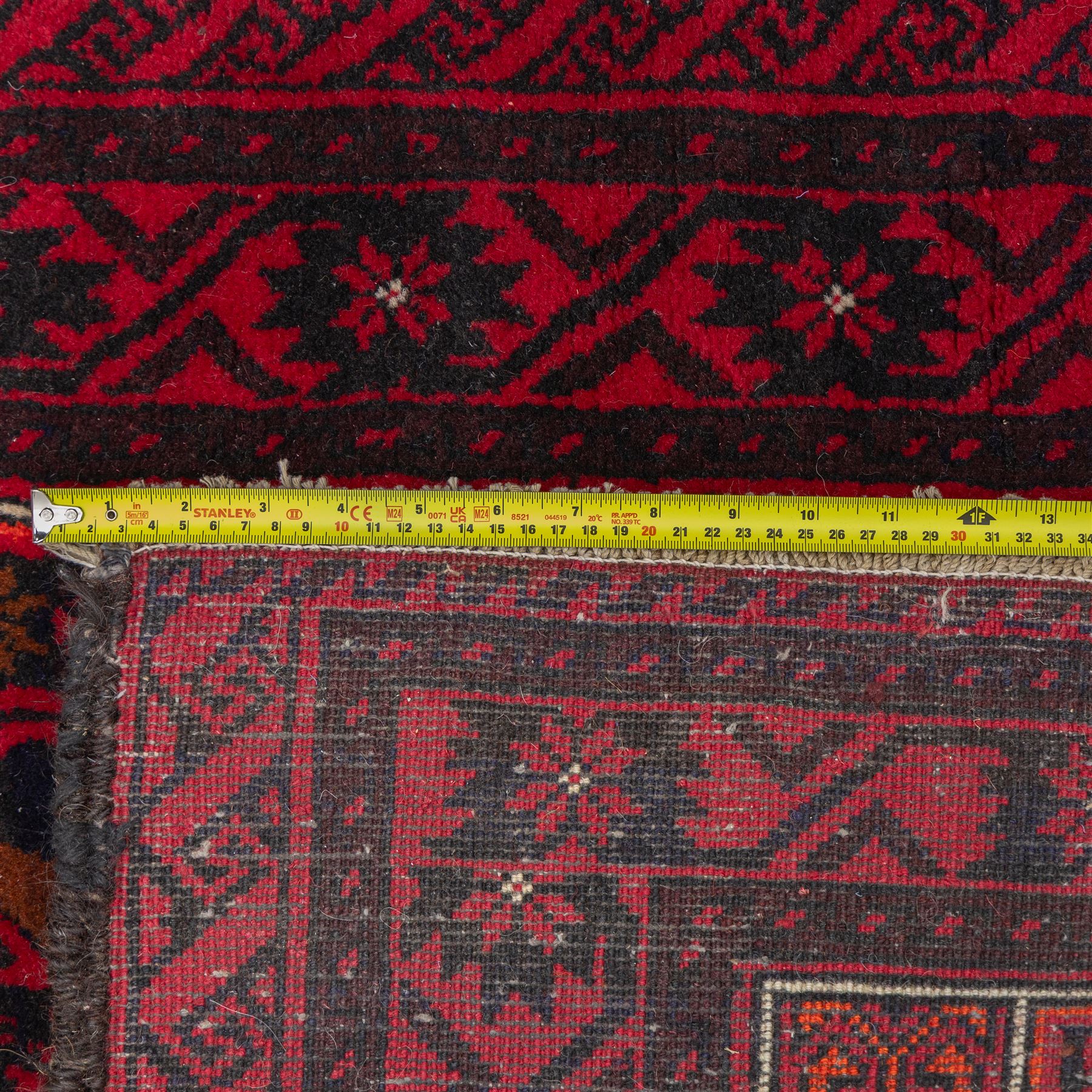 North east Persian Baluch hand-knotted runner, crimson ground with a vertical column of hooked lozenge medallions flanked by stylized leaf motifs within multiple geometric borders of rosettes and angular vines  