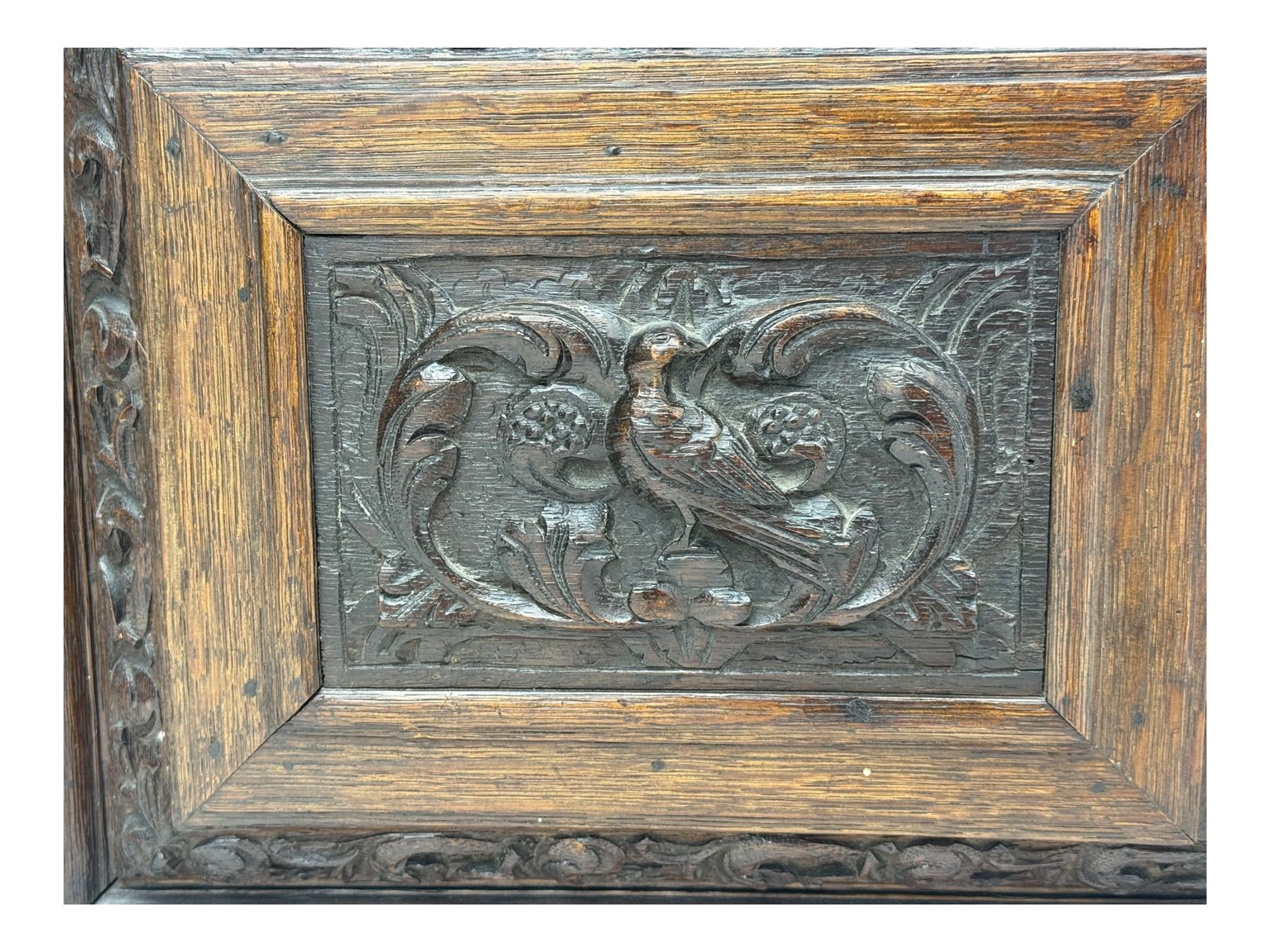 18th century and later carved oak cupboard, enclosed by panelled door carved with central bird motif and scrolled leafage with an outer ebony band, the frieze and uprights carved with repeating lunette and floral designs, flanked by scrolled foliate carved upright brackets