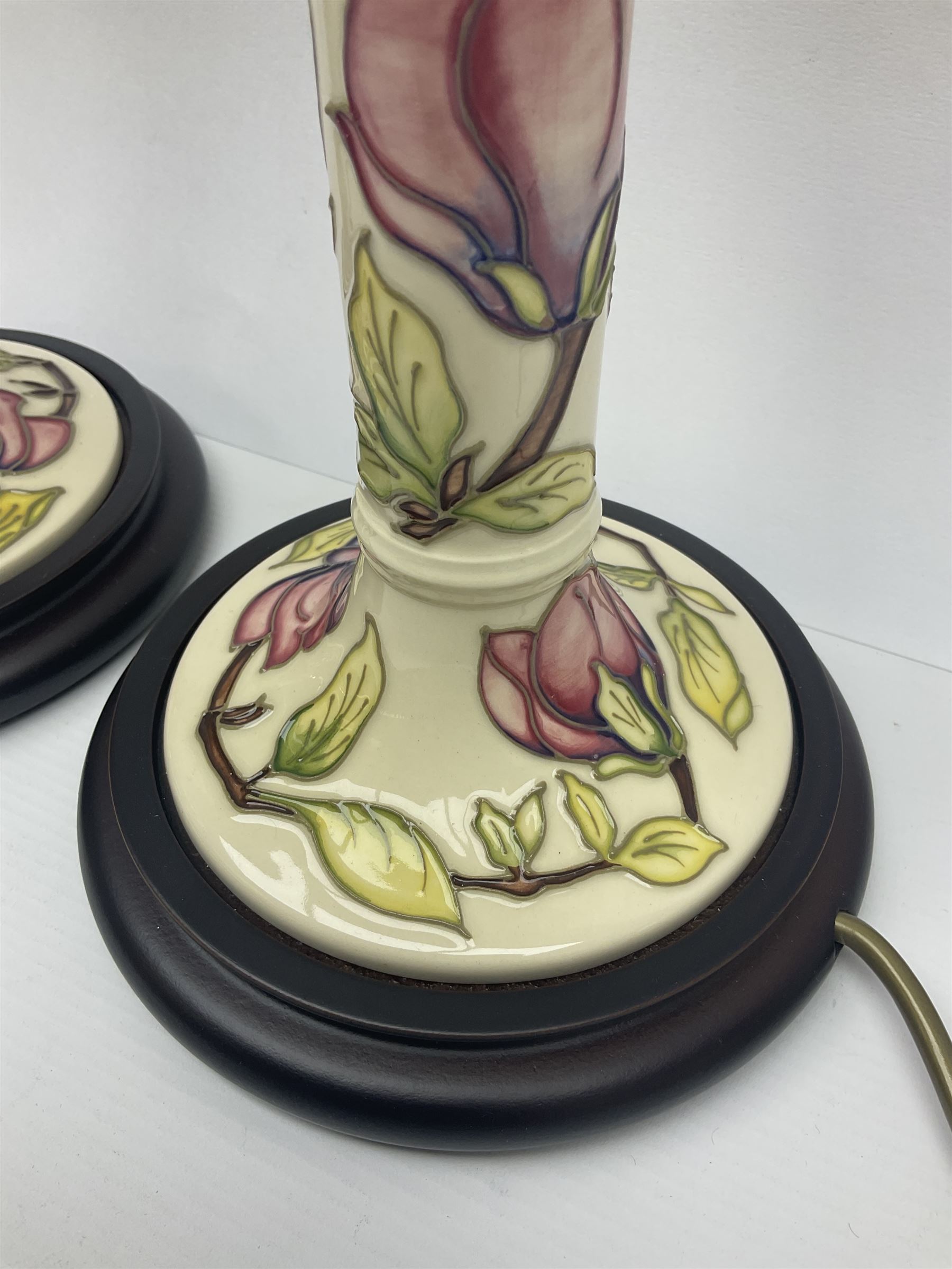 Pair of Moorcroft table lamps of candlestick form in magnolia pattern, with Moorcroft shades, H50cm 
