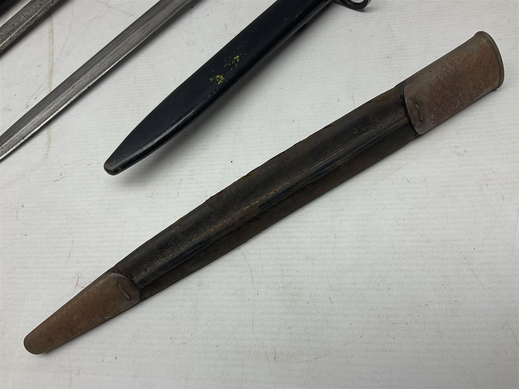 British No 7 MKI knife bayonet with 20cm single edged fullered clipped point blade;  blackened steel, large muzzle ring cross-guard; blackened swivelling pommel marked 'F5H'; red Tufnol composite grips; in blackened steel scabbard L33cm overall; British Pattern 1888 bayonet with scabbard; and German Ersatz bayonet with scabbard (3)