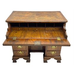 Early 18th century Queen Anne figured walnut kneehole desk with secretaire drawer, moulded and book matched top with walnut band, the top drawer with fall front enclosing small drawers and pigeon holes, fitted with nine drawers and central recessed cupboard, on ogee bracket feet