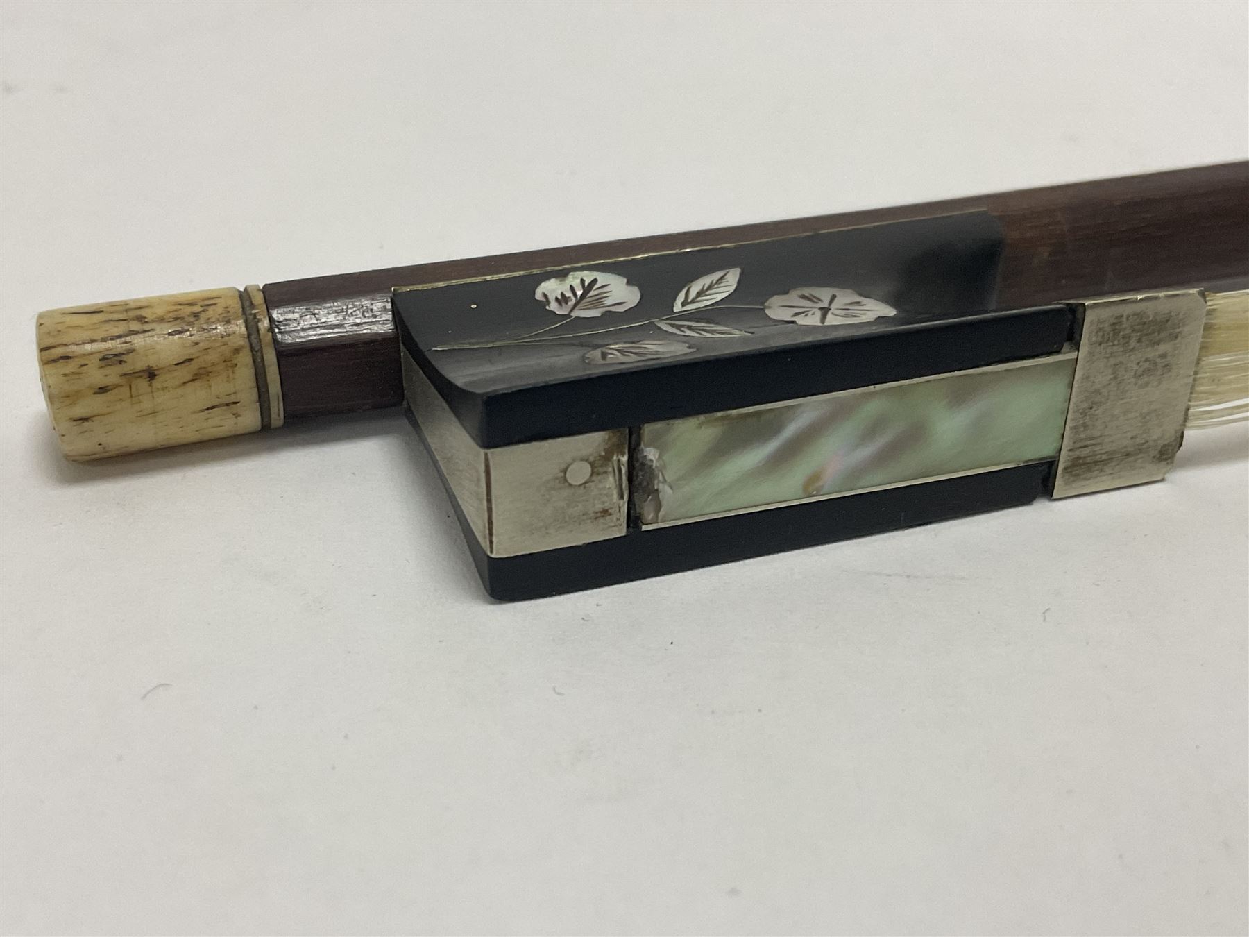 19th century wooden violin bow with a decorative mother of pearl inlay depicting flowers to the frog, with a bone adjuster screw