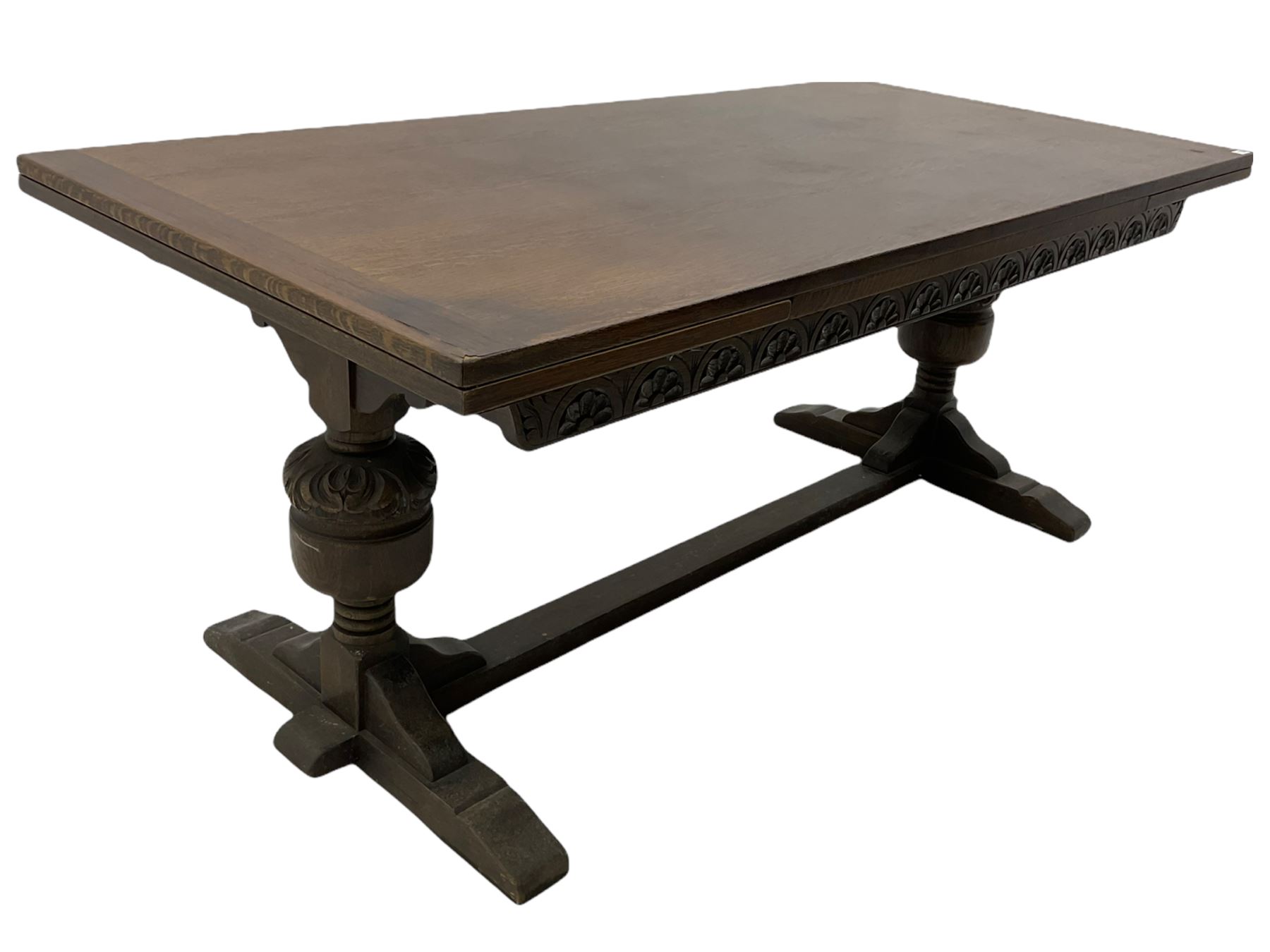 20th century oak drawer leaf extending dining table, two foliage carved baluster supports on sledge feet joined by floor stretcher 