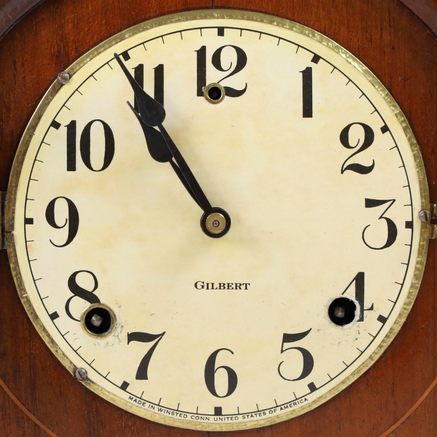 Gilbert Clock Company eight-day mahogany cased mantle clock, with a cream card dial, break arch top, upon a raised plinth, H28cm