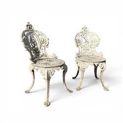 Pair of white painted cast metal garden chairs, ornate reclined backs, circular pierced seats on cabriole legs