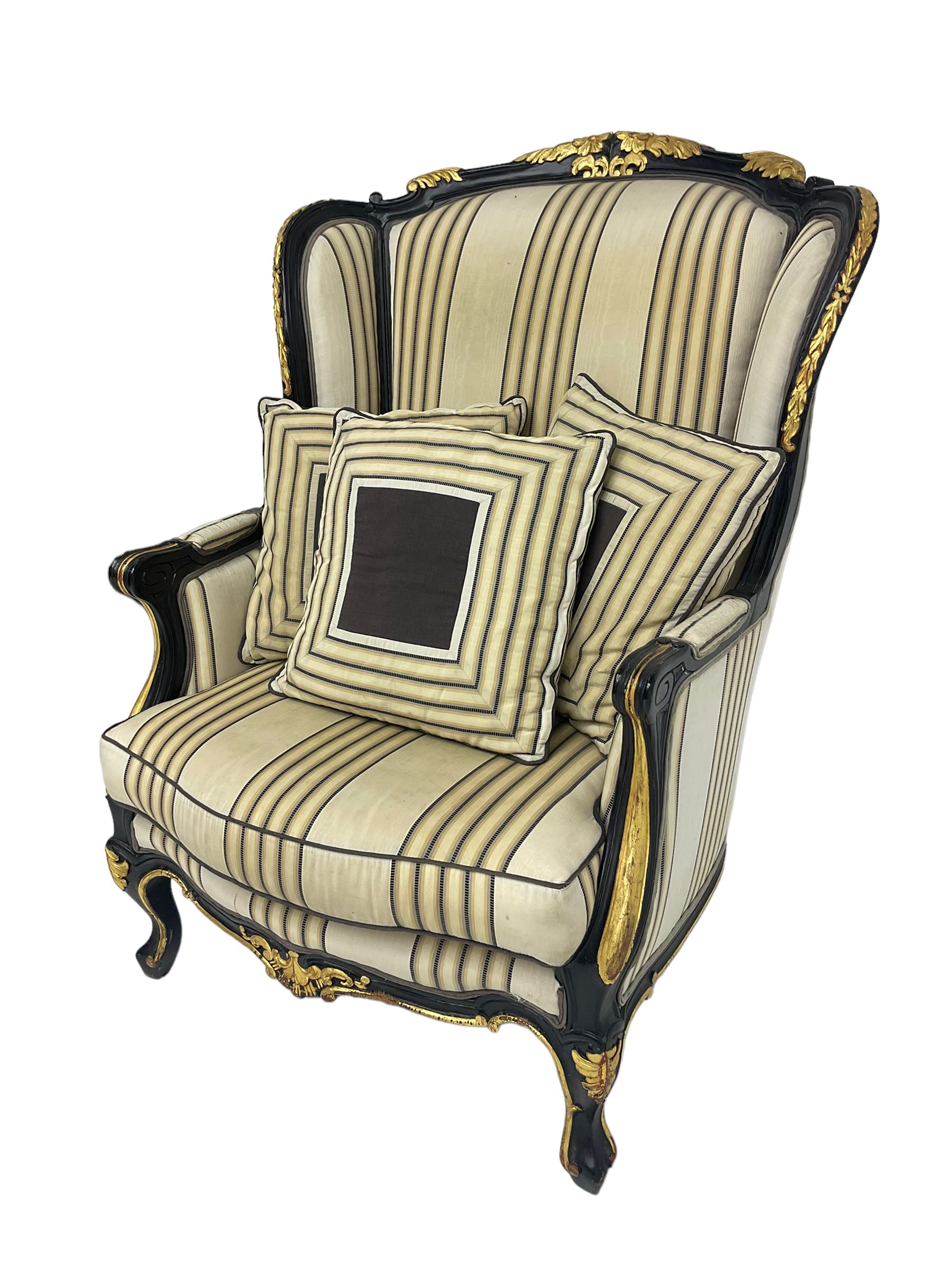 Thomas Messel - Georgian style ebonised and gilt wingback armchair, upholstered in striped fabric, on cabriole front feet