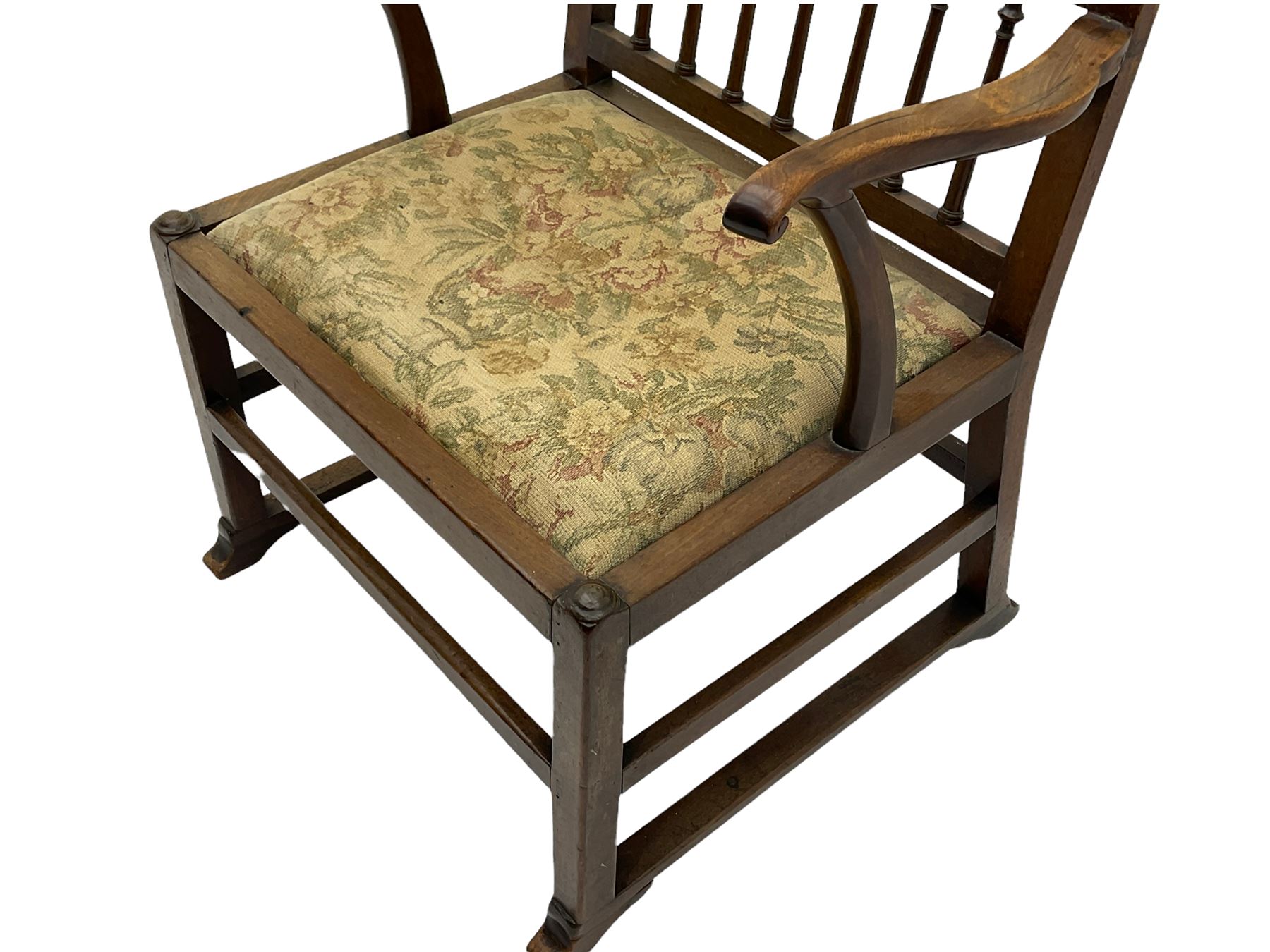 Late 18th century walnut 'Drunkard's' chair, the shaped cresting rail over spindle back, wide set seat with upholstered drop in cushion, shaped arms with scroll carved terminals, sledge supports with bracket feet joined by plain stretchers 
