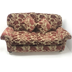 Two seat sofa upholstered in a patterned red and gold fabric, turned supports on castors (W130cm) and an armchair upholstered in a red and gold stripped fabric, turned supports on castors (W102cm)