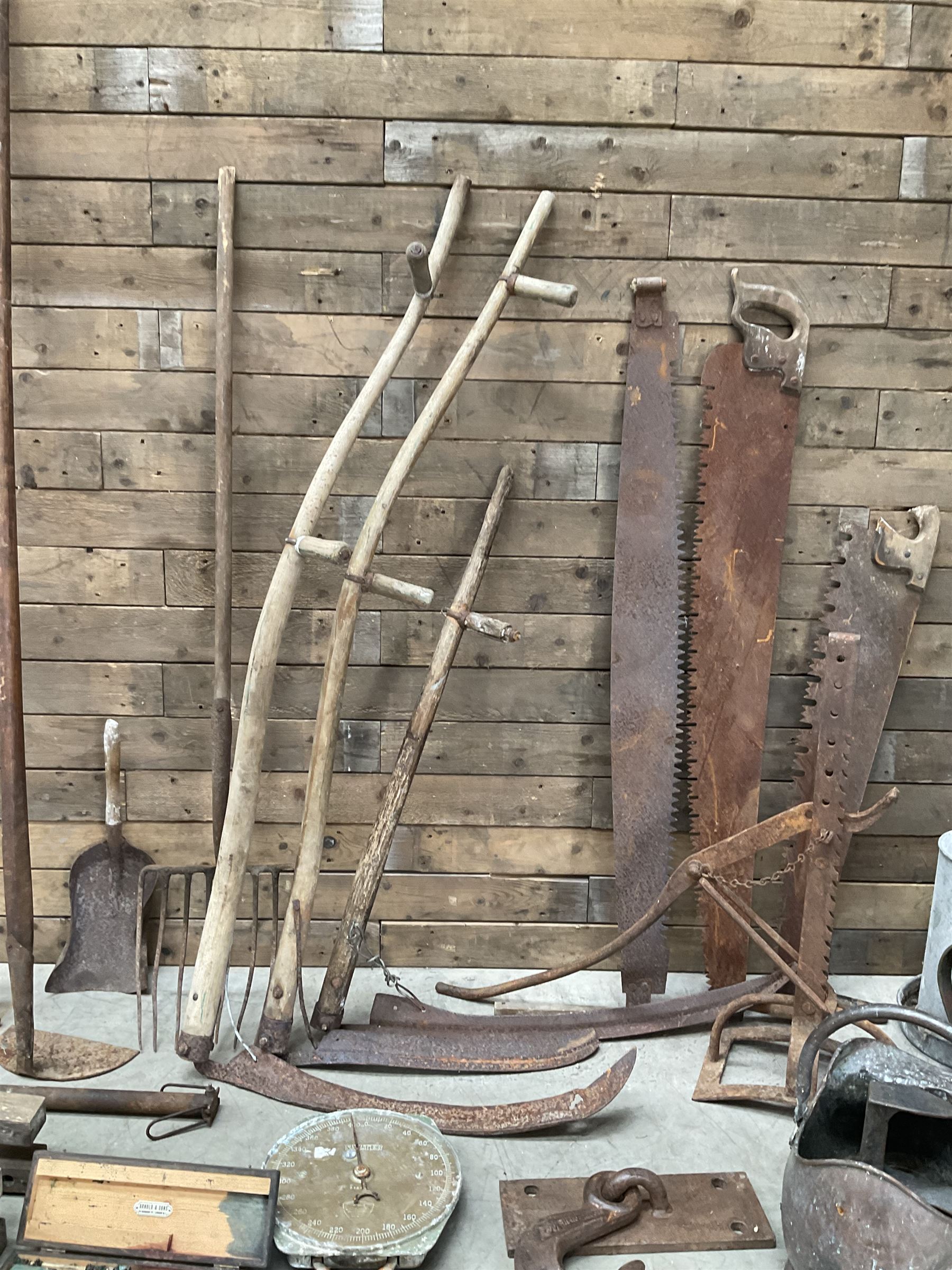 Large quantity of vintage hand tools including scales, scythes, saws etc