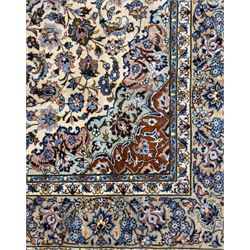 Central Persian Najafabad hand-knotted carpet, the ivory field with a central floral medallion radiating palmettes and arabesques in tones of blue, lilac and tan, enclosed by a wide navy border of scrolling vine and rosette motifs, with red spandrels and multiple guard stripes