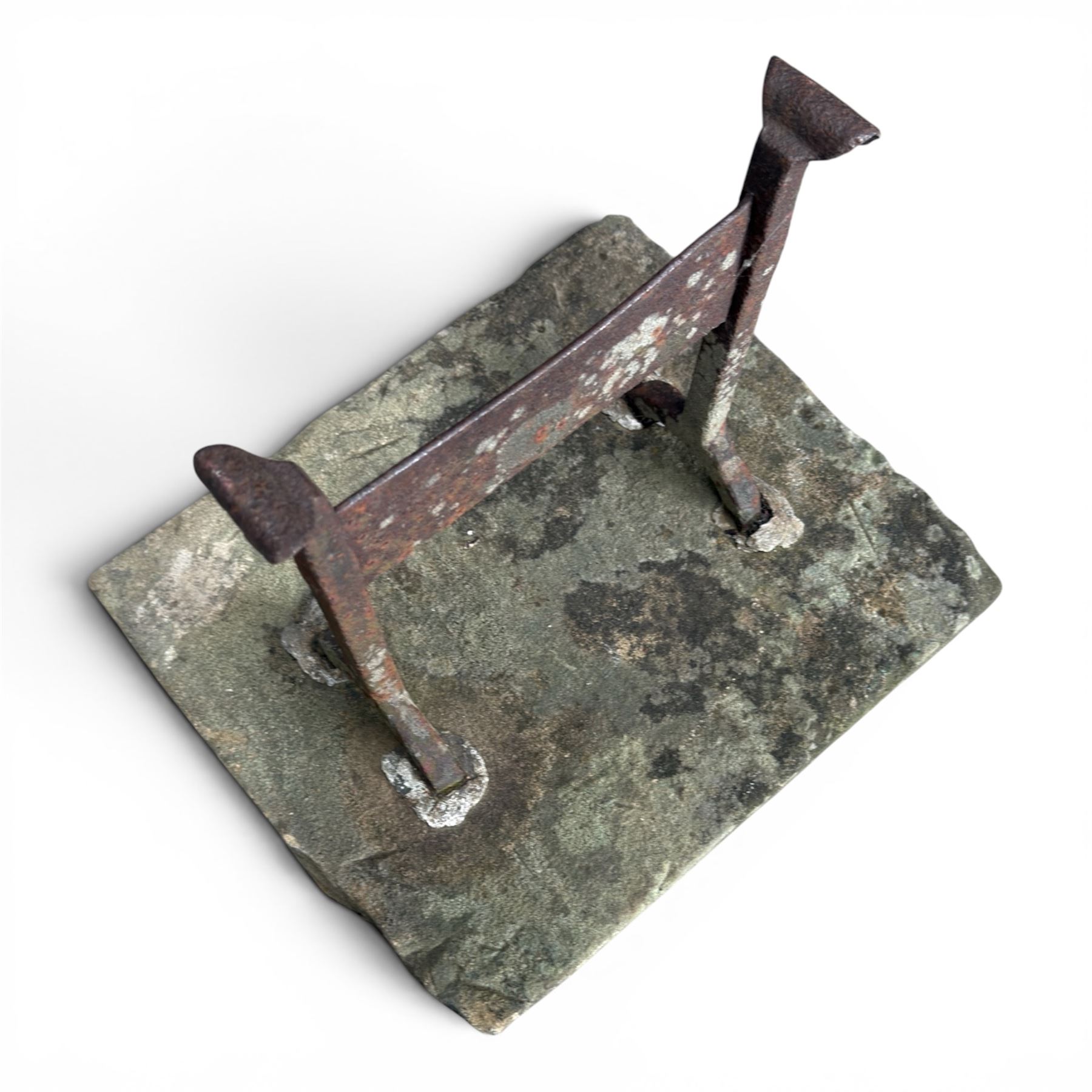 19th century cast iron boot scraper, mounted on a rectangular hewn stone slab base, with scrolled twin upright supports and scraper bar, in weathered finish
