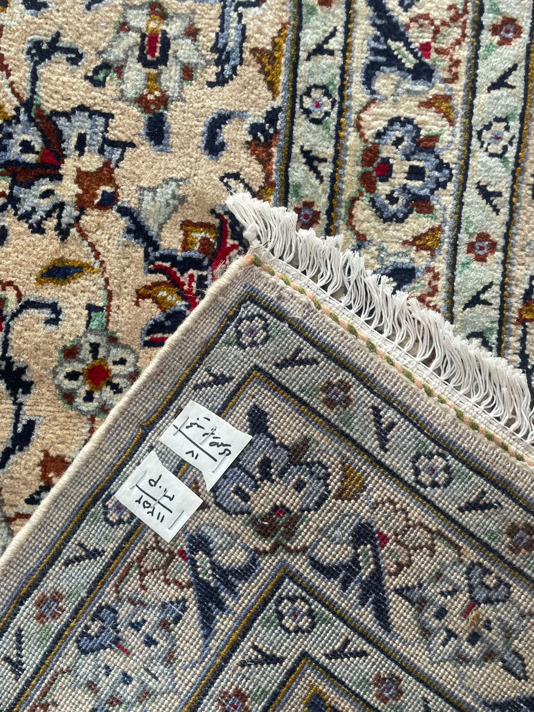 Persian Kashan ivory ground carpet, the field decorated with interlacing foliate branches and stylised plant motifs, scrolling border decorated with repeating palmettes, within floral pattern guard bands