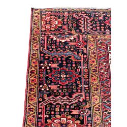 Antique Persian coral ground carpet, the large central floral pole medallion with extending foliate designs, the thick guarded indigo border with repeating flower heads and circles