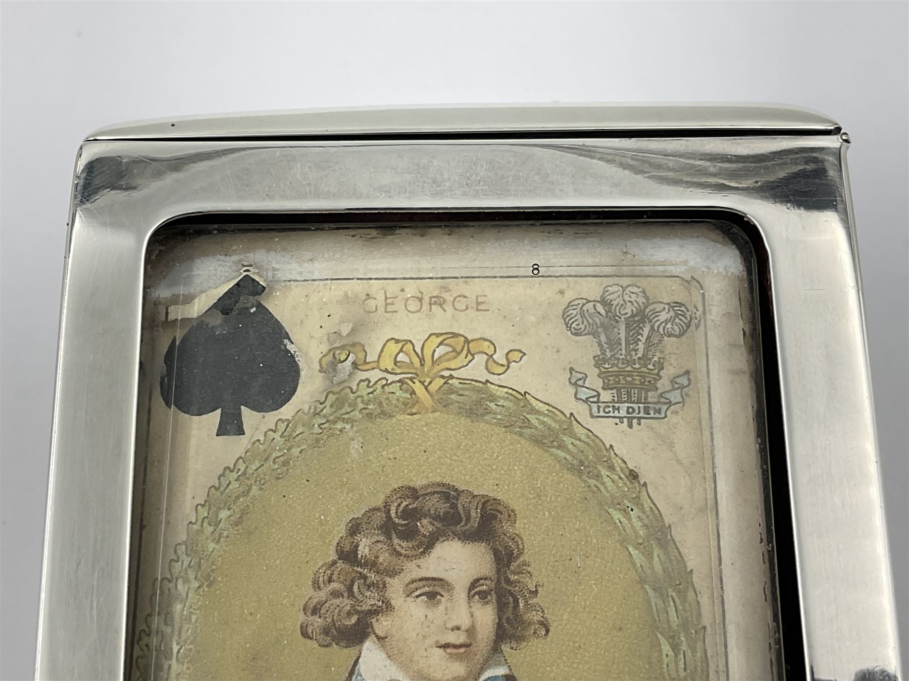 Edwardian silver mounted playing card case, hallmarked William Harrison Walter, Birmingham 1903, the sides each with a period playing card set behind a bevelled glass panel, the hinged cover with later engraving 'Presented to Norman T Crombie Esq by the officers & men of the 31st WR Detachment for services rendered 1917-1918', with red leather lined interior, the three compartments upon a sprung base and containing two later wooden Whist markers, case H12.5cm