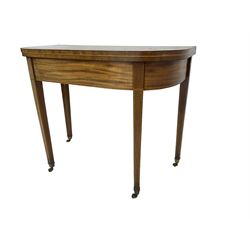 Early 19th century mahogany demi-lune card table, swivel fold-over top with satinwood band and baize lined interior, on square tapering supports with brass cups and castors