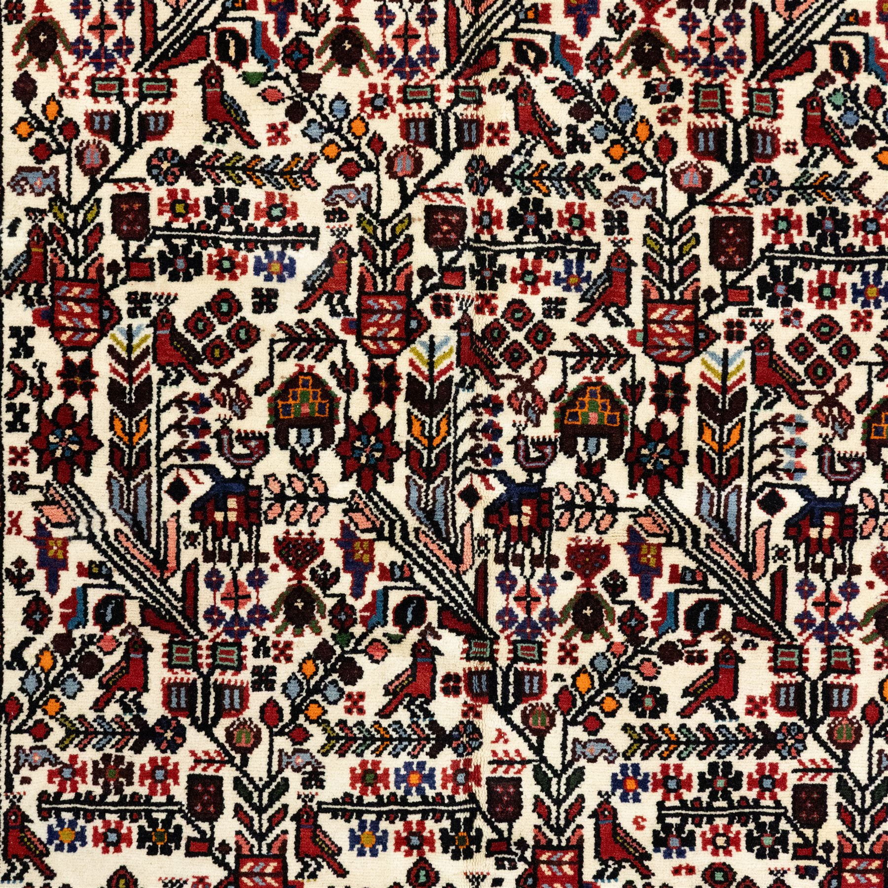 North west Persian Rudbar hand-knotted rug, ivory field woven with a repeating pattern of stylized shrubs, rosettes, and geometric floral motifs in tones of madder red, turquoise, indigo, and ochre, enclosed by a border of linked rosettes and angular flowerheads between narrow guard stripes 