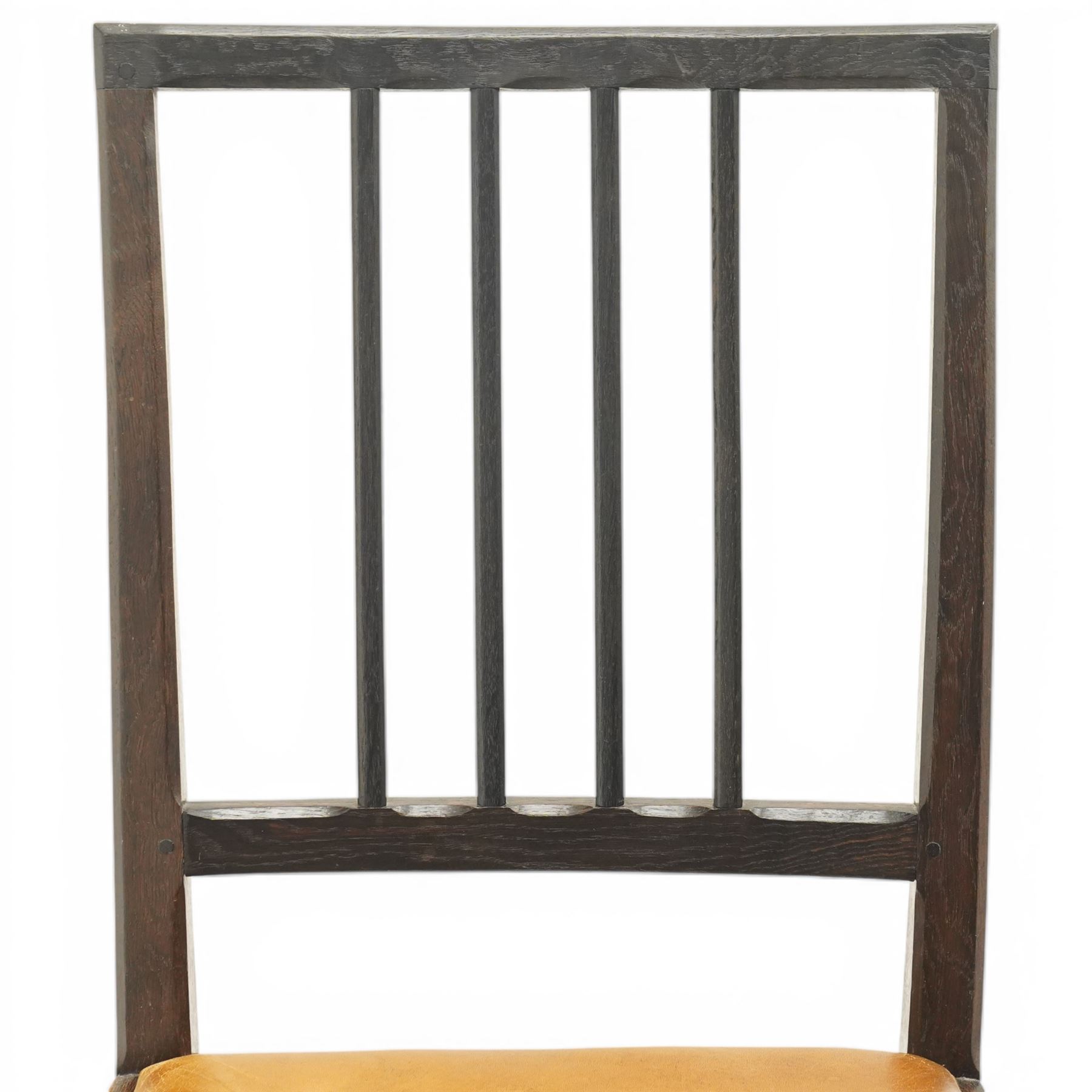 Acornman - set of four dark stained oak dining chairs, with four vertical slats, drop-in tan leather seat, supported on square tapering legs with carved acorn signature, by the workshop of Alan Grainger of Brandsby