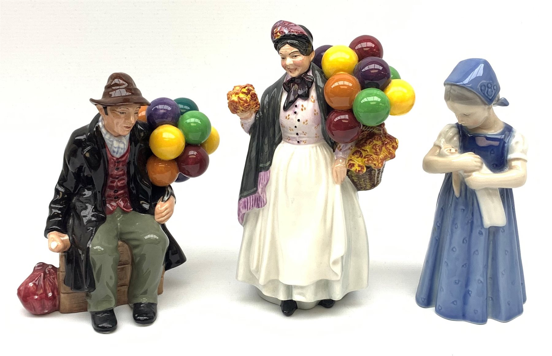 Royal Copenhagen figure of a young girl holding a doll and two Royal Doulton figures: Biddy Penny Farthing and The Balloon Man (3)