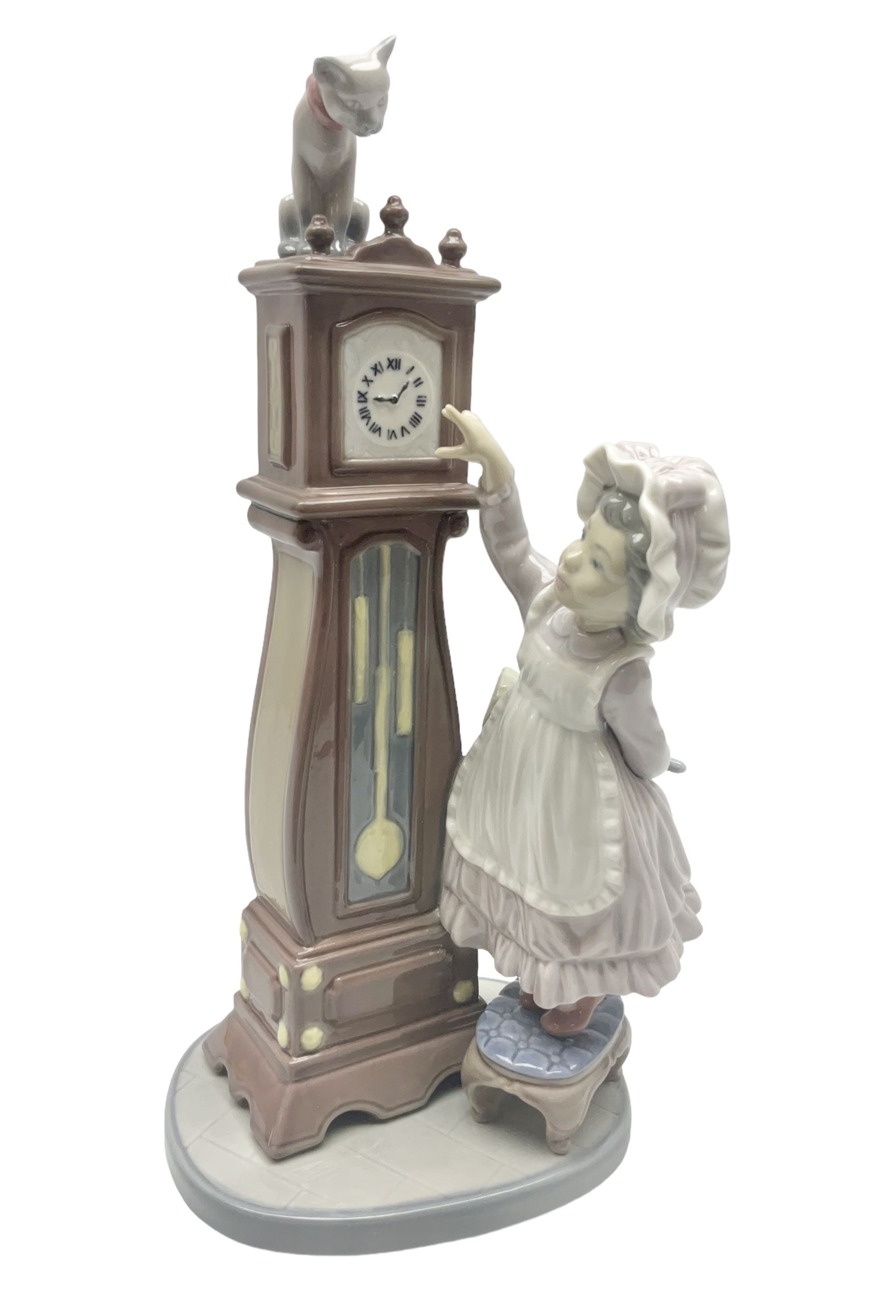 Lladro figure, Bedtime, modelled as a young girl reaching for her pet cat upon grandfather clock, sculpted by Vincente Martinez, with original box, no 5347, year issued 1986, year retired 1998, H28cm