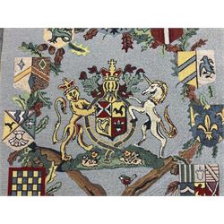 Three tapestries comprising 20th century wool tapestry panel of a medieval nobleman upon a horse with a castle in the distance, together with a smaller tapestry depicting The English Coat of Arms, both hung on rails, and further depicting village scene, largest approx 132cm x 95cm
