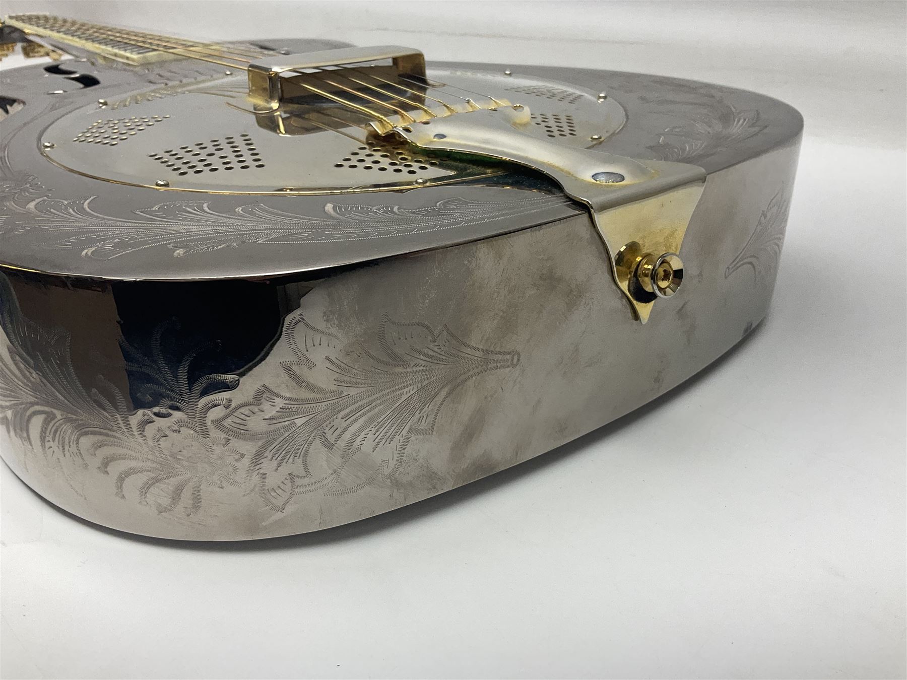 Ozark metal cased resonator guitar with all over chased foliate decoration to the polished finish and mother-of-pearl inlay to the fretboard L100cm; in Stagg hard carrying case