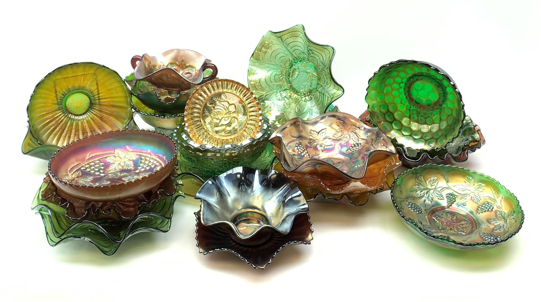 A collection of Carnival glass, to include marigold, green, and amethyst, bowls, dishes, and comports, various patterns including fruiting vines, peacocks, and an example decorated with a Horseshoe and detailed Good Luck. 
