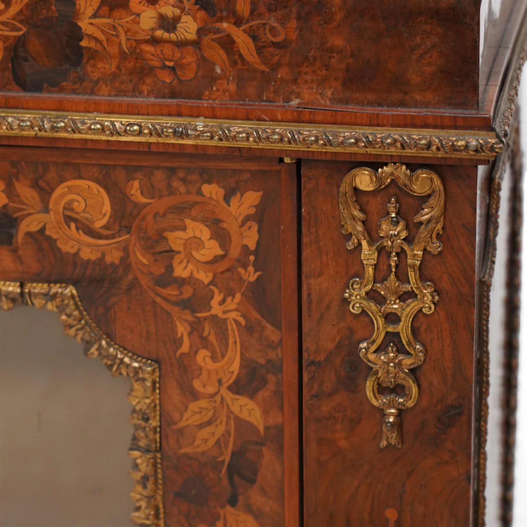 Victorian walnut and gilt metal mounted pier cabinet, rectangular top over acanthus leaf moulded gilt metal edging and floral inlaid frieze, single glazed door inlaid with scrolling leafage and flower heads, fitted with single internal shelf, egg and dart moulded lower edge over shaped skirt base 