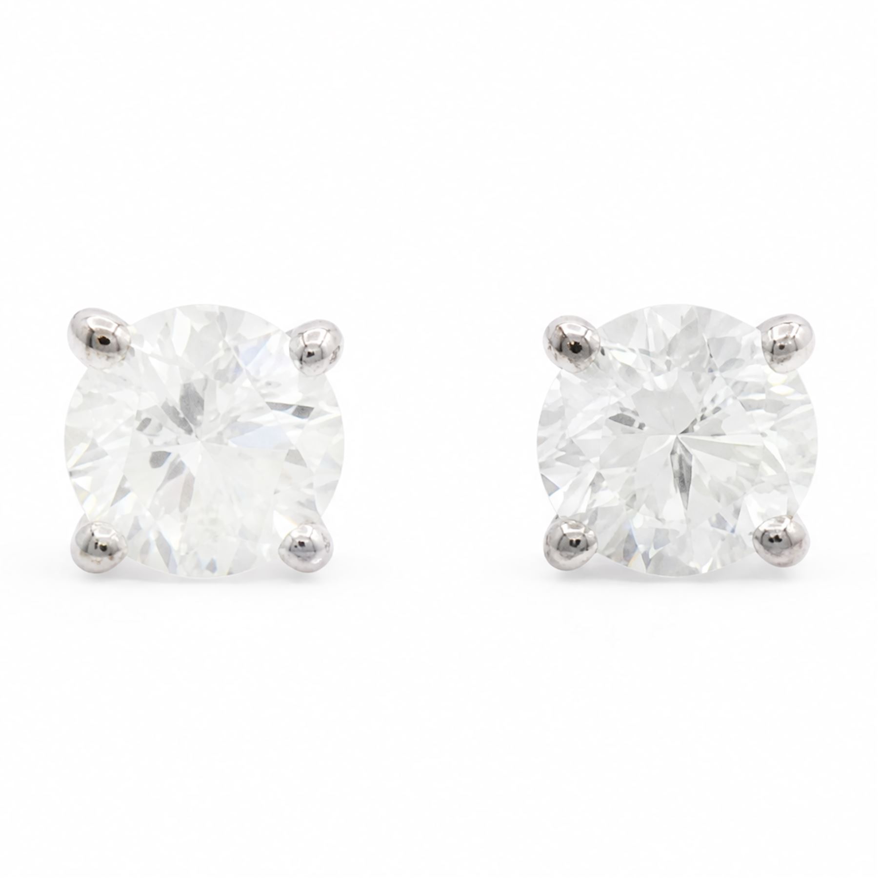 Pair of 18ct white gold diamond earrings, each stud four claw set with a single round brilliant cut diamond, stamped 750, total diamond weight approx 1.05 carat