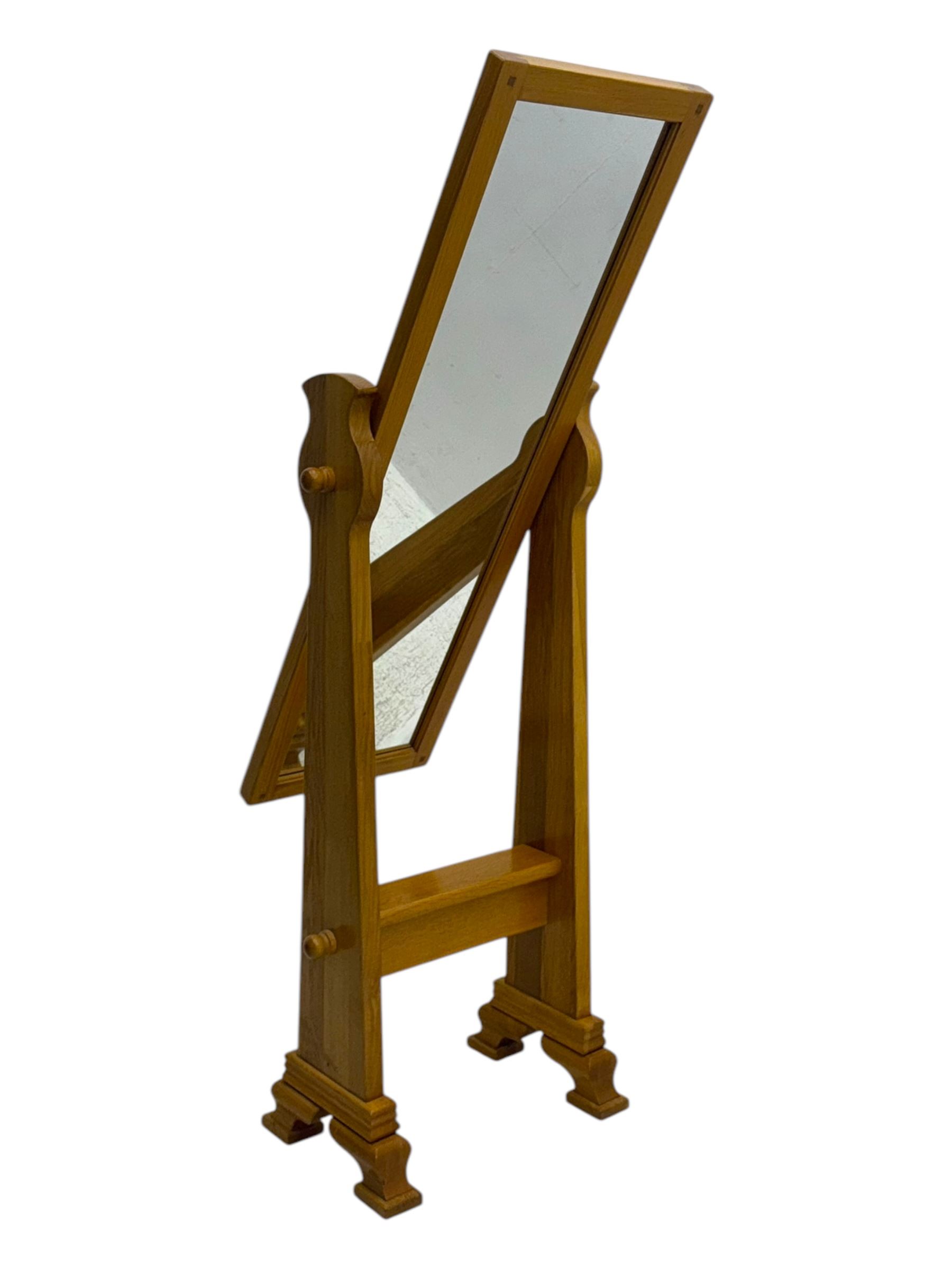 Contemporary light oak cheval dressing mirror, rectangular frame enclosing plain mirror plate, on shaped supports with turned finials, raised on stepped bracket feet