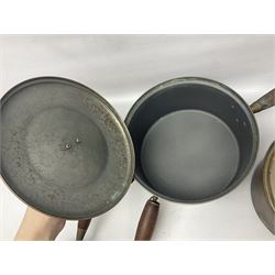 Four Victorian copper moulds, together with a graduating set of copper pans with wooden handles and finials to covers, largest pan 