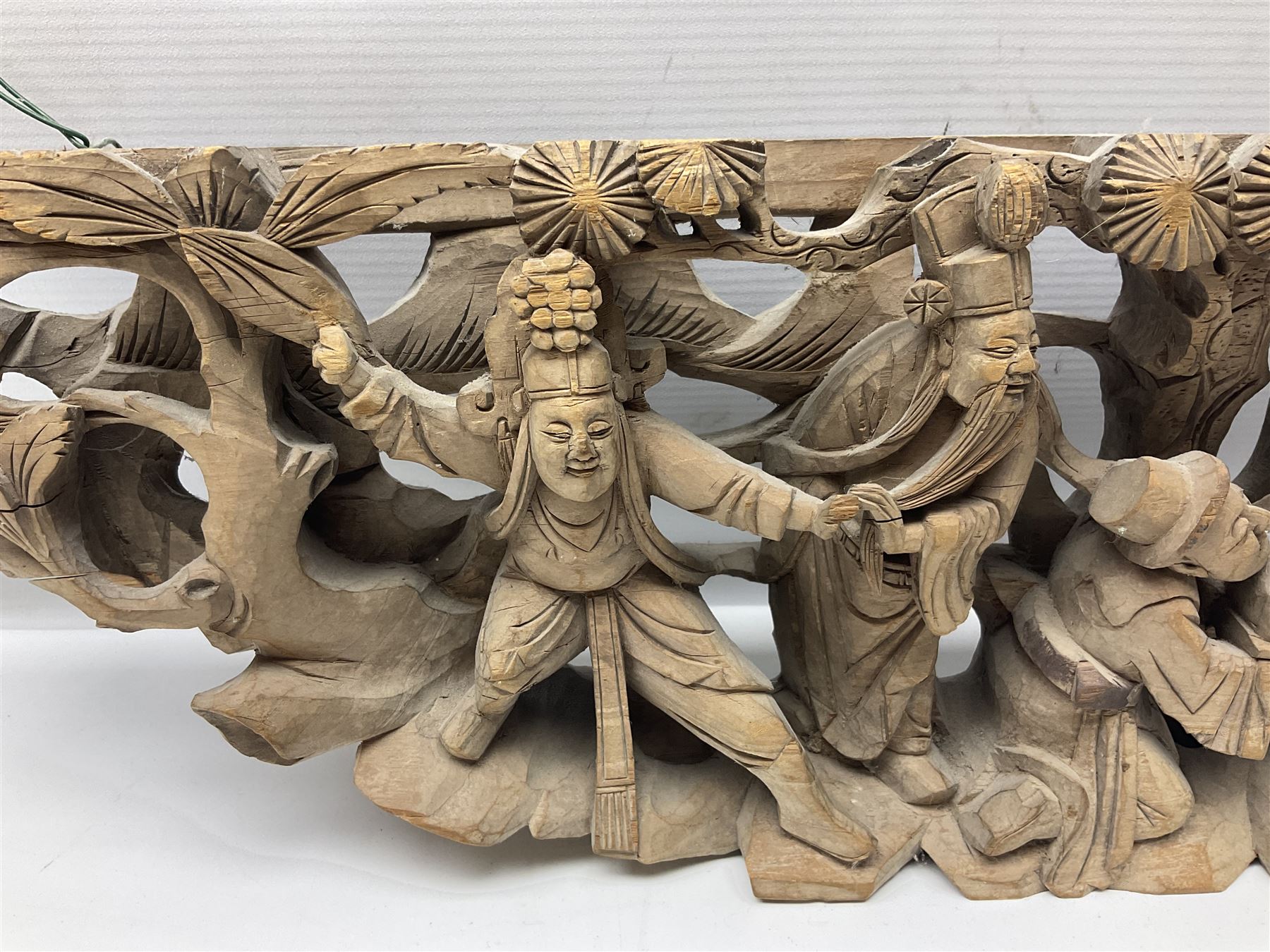 Two carved oriental wall hangings, the first example gilded depicting a temple and garden scene, the second figures in a garden, L49cm