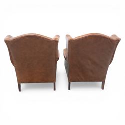 Laura Ashley - Pair of brown leather wingback armchairs, with scrolled arms and loose cushion seat, brass studded trim, on cylindrical tapering legs terminating in castors