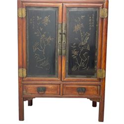 Late 19th century Chinese Qing dynasty red and black lacquered wood cabinet,  Fujianese province, upper cupboard enclosed by two doors with relief carved and gilt panels depicting figures behind glass, the large cupboard enclosed by two panelled doors carved with trailing foliate branches and birds, inscribed with Chinese characters, to the left ‘The red mountains are in the shape of Phoenixes and appear auspicious’ and to the right, ‘Wealth and honour are given by flowers and I hear the sound of the phoenix', fitted with two drawers, on square supports with carved brackets 